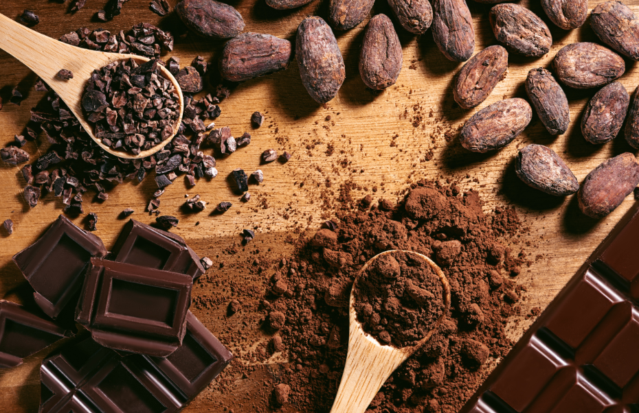 Wooden board with a collection o key ingredients to make home made protein bars with cocoa powder, dark chocolate, nuts and chia seeds